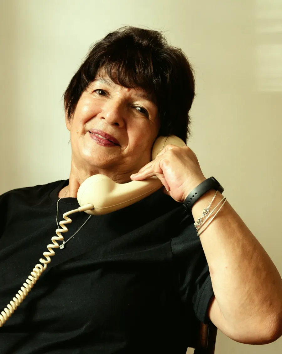Eine Seniorin telefoniert lächelnd mit einem Festnetztelefon.